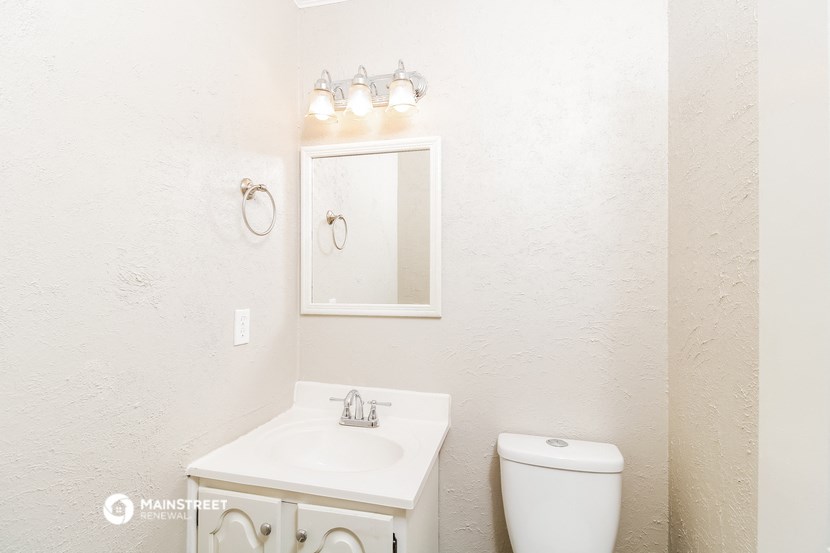 the bathroom has a white sink and toilet and a mirror