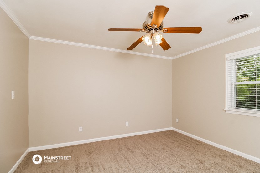 the bedroom has a ceiling fan and a carpet
