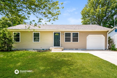 a yellow house with a green front door and a lawn