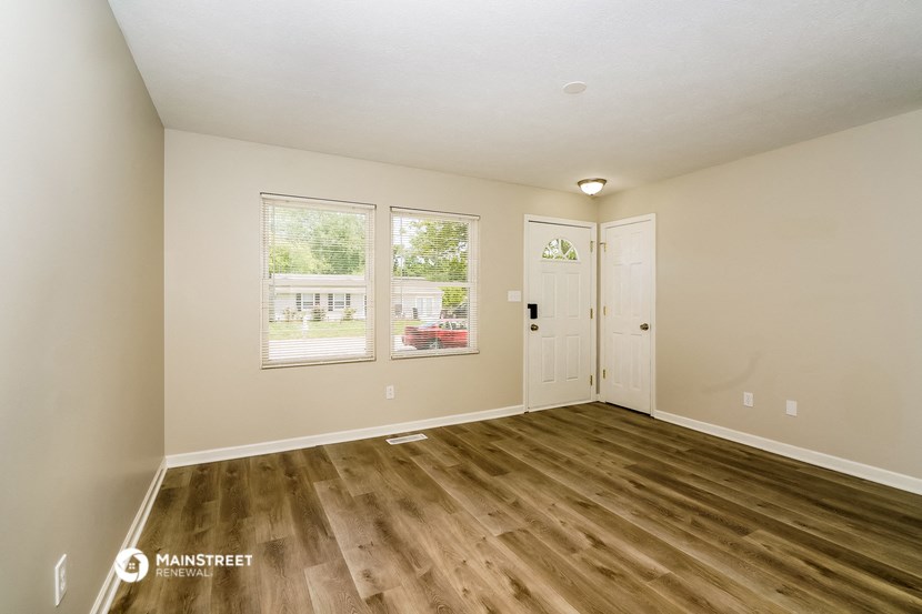 the spacious living room with hardwood flooring and white walls