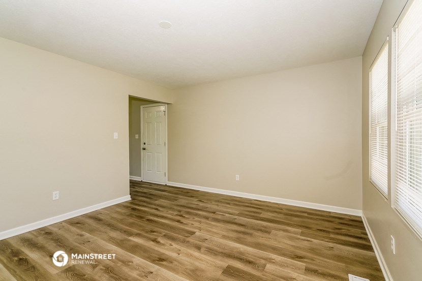the spacious living room with wood flooring and white walls