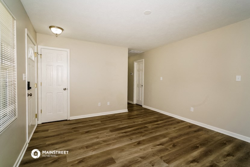 the spacious living room with wood flooring and white walls