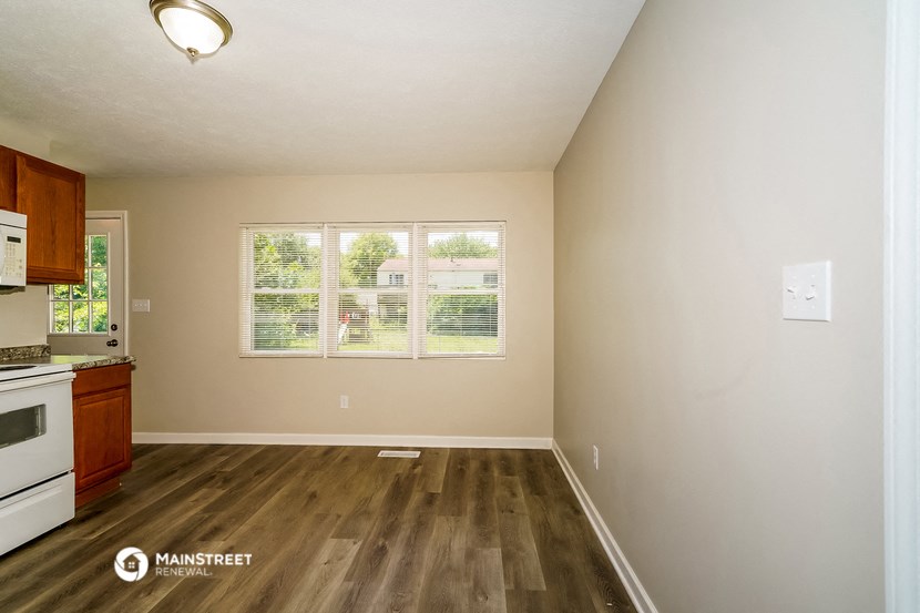 an empty kitchen with a large window and wood flooring