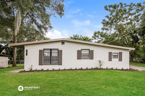a small white house with a lawn and trees