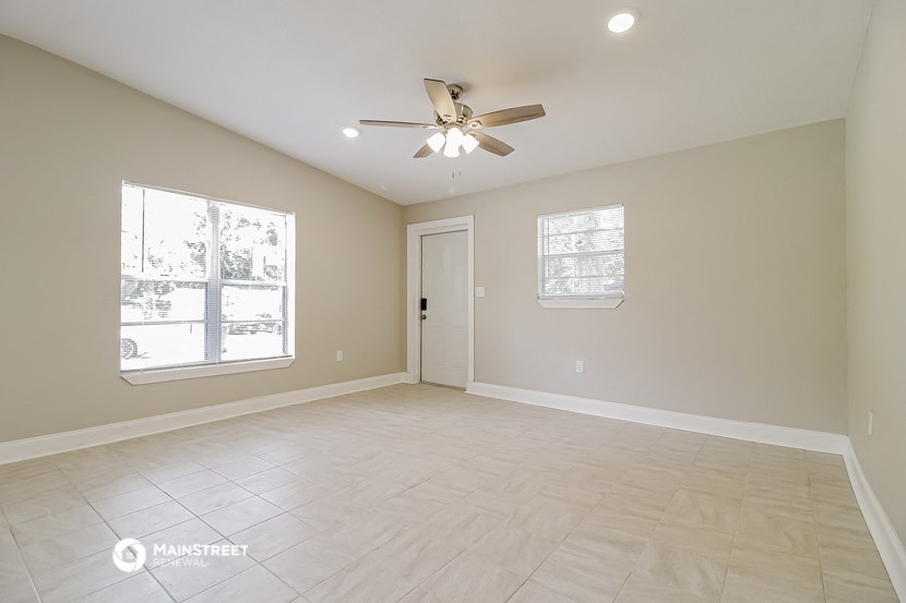 an empty living room with a ceiling fan and a window