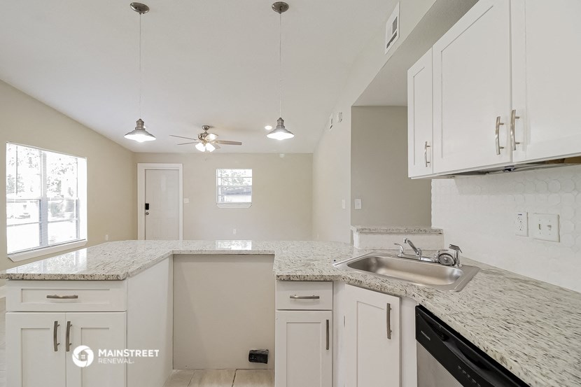 a kitchen with white cabinets and granite counter tops and a sink