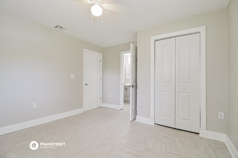 an empty living room with white doors and a white door to a bathroom