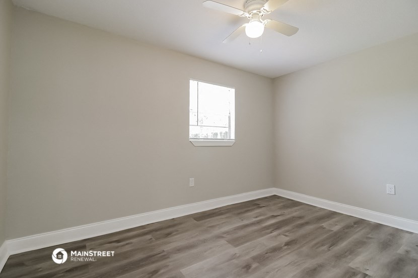 an empty room with a ceiling fan and a window