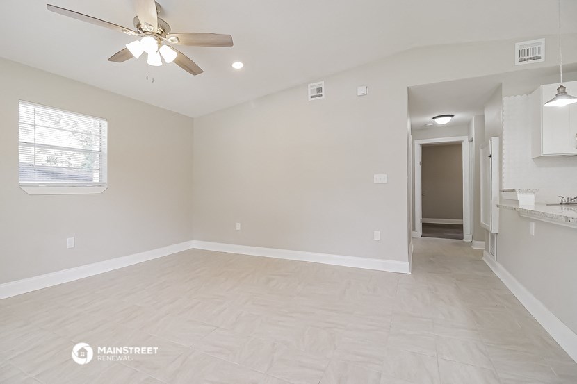 an empty living room and kitchen with a ceiling fan