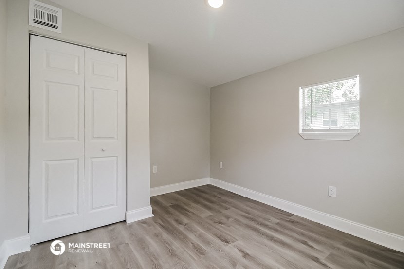 a bedroom with a white door and wood flooring