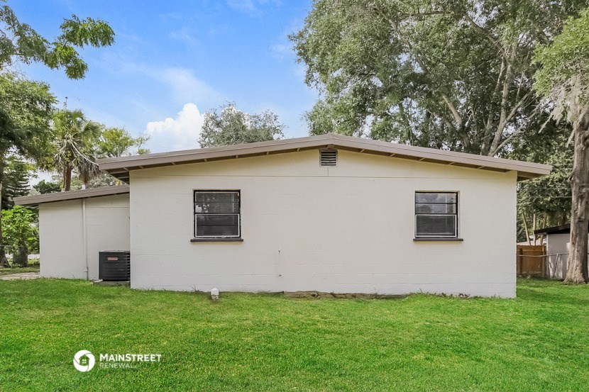 a small white house with a lawn and some trees