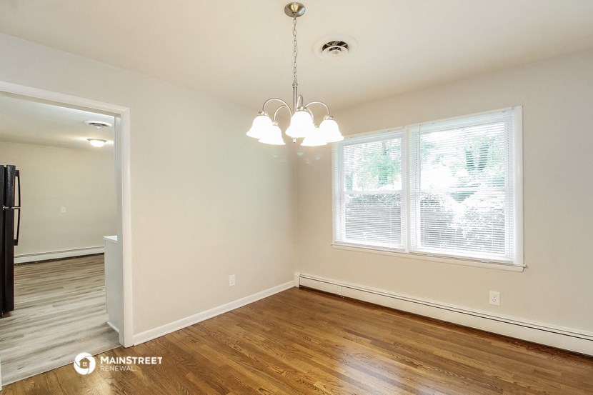 the living room of an empty house with wood flooring and a large window
