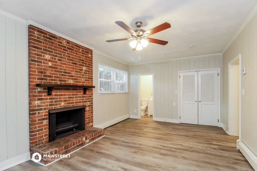 a living room with a brick fireplace and a ceiling fan