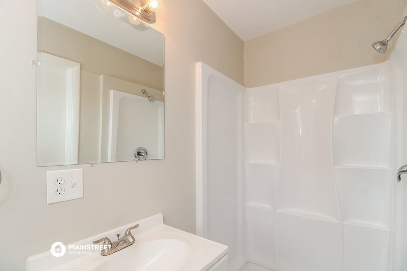 a bathroom with a sink and a shower and a mirror
