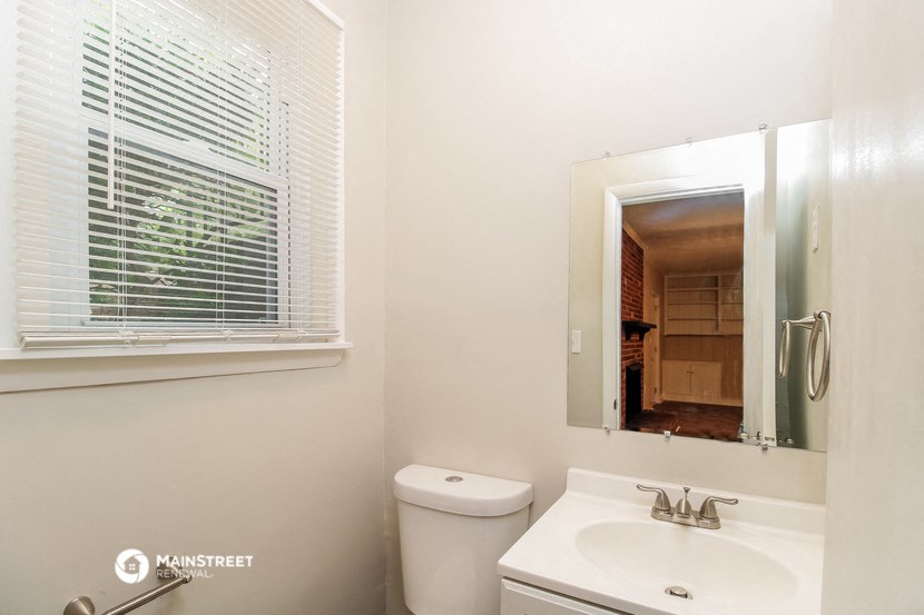 a bathroom with a toilet sink and a mirror and a window