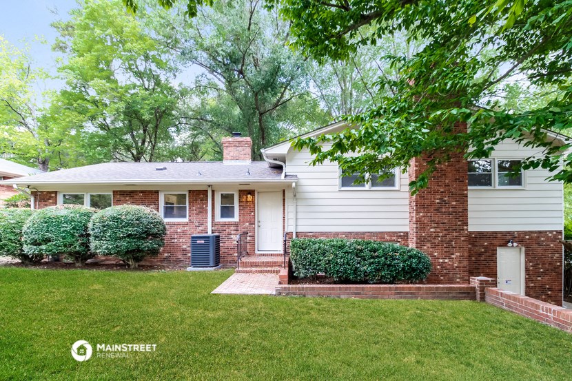 a white and brick house with a lawn and trees