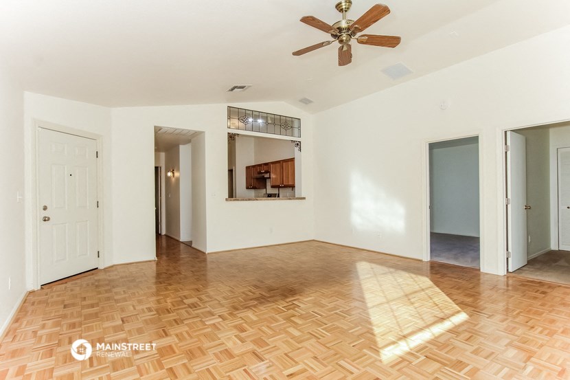an empty living room with a ceiling fan and a mirror