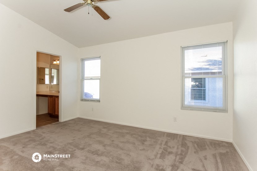 an empty living room with a ceiling fan and a window
