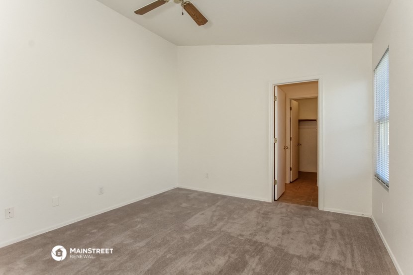 an empty living room with carpet and a ceiling fan