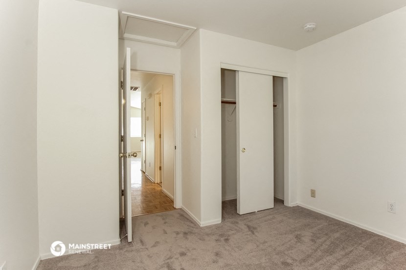 a bedroom with three closets and a door to a hallway