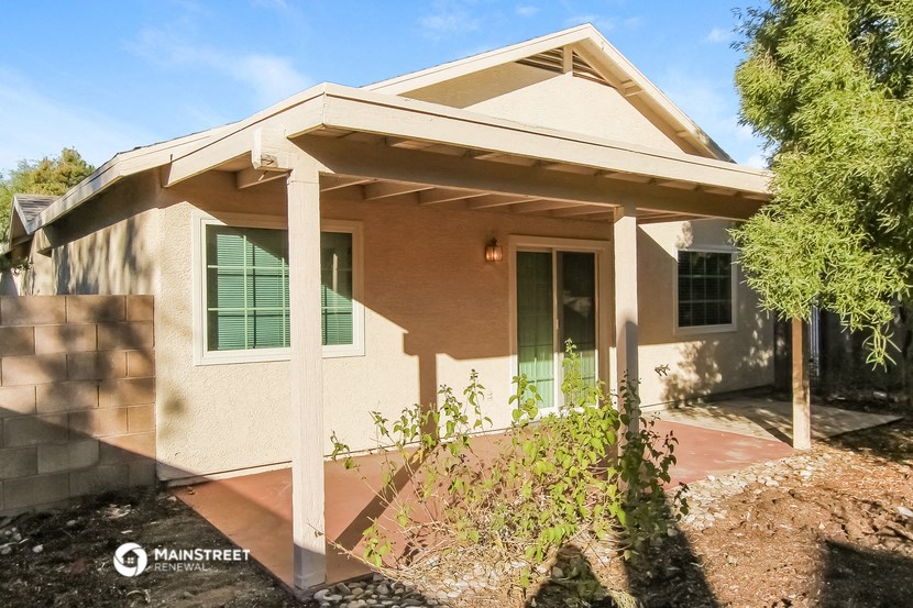 the front of a house with a porch and a tree