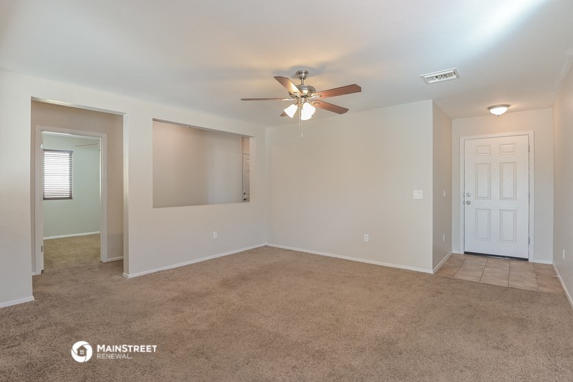 the living room of an empty house with a ceiling fan