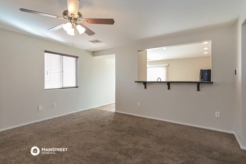 the spacious living room with carpet and ceiling fan