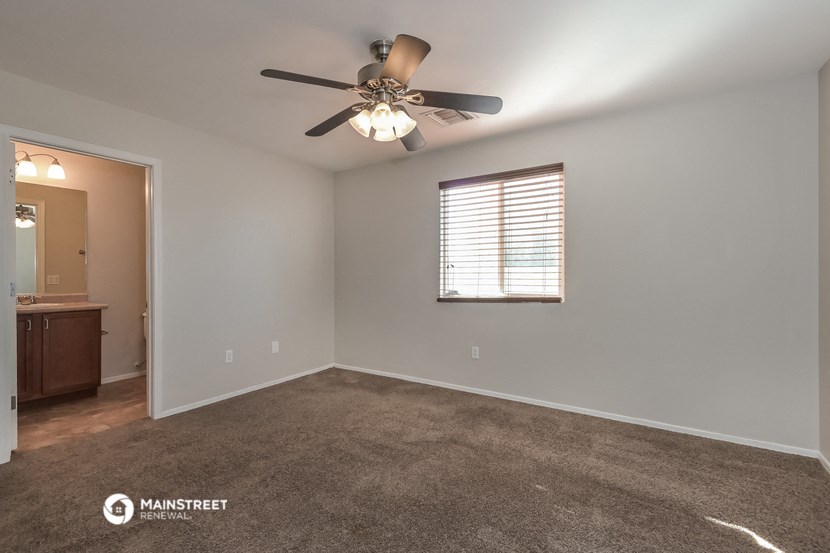 the spacious living room with ceiling fan and carpet