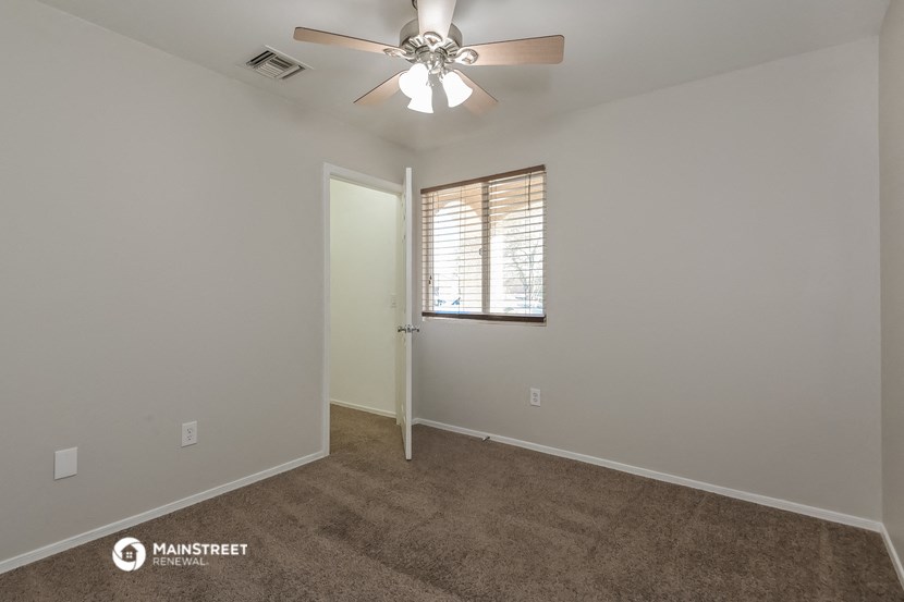the spacious living room with carpet and ceiling fan