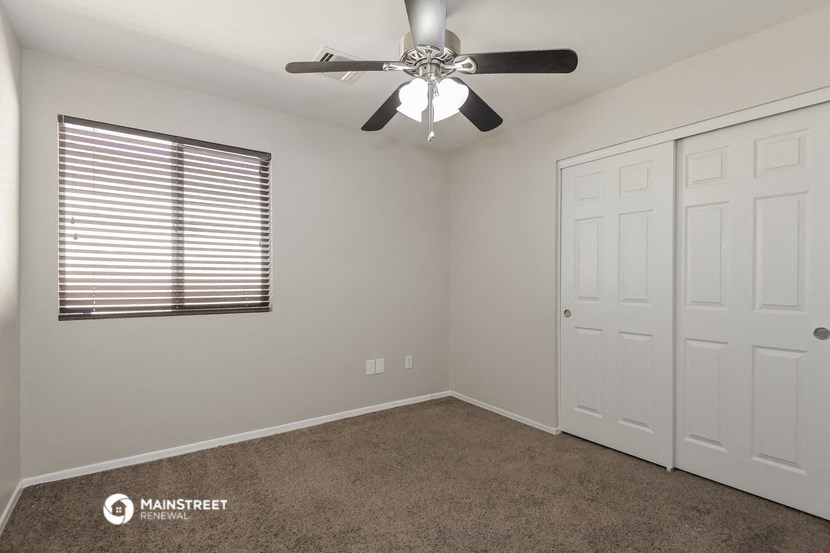 the bedroom has a ceiling fan and a closet