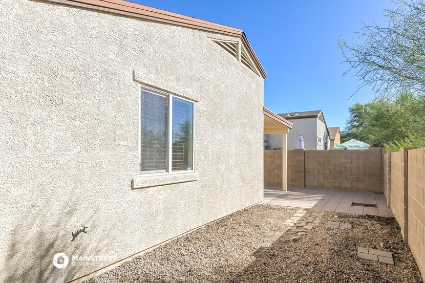 a side view of a white brick house with a yard and a window