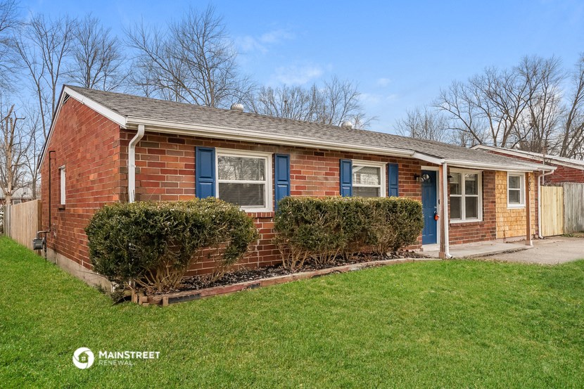 a small brick house with blue shutters and a lawn