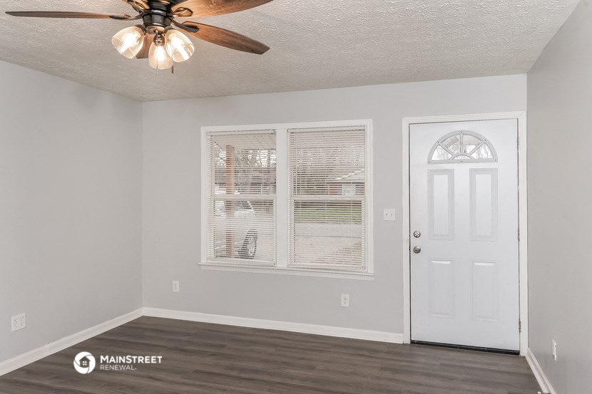 the living room of an empty house with a ceiling fan