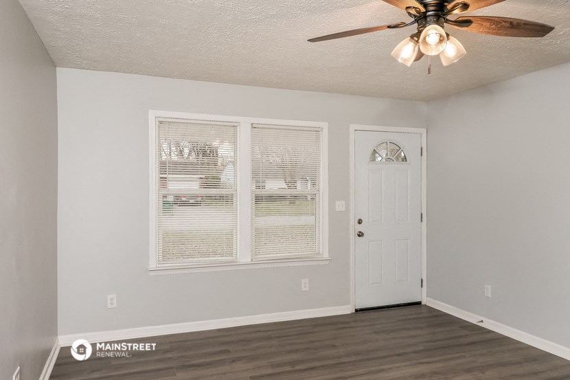 the living room of an apartment with a ceiling fan and a door