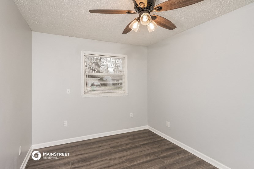 the living room of an apartment with a ceiling fan and a window