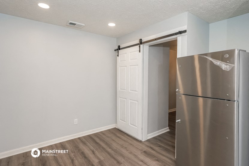 a room with a refrigerator and a door to a closet