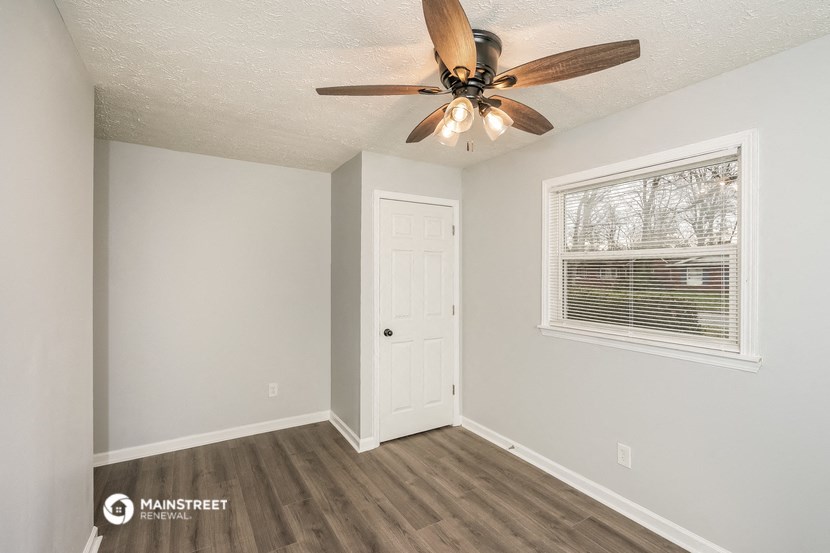 the bedroom has a ceiling fan and a door to the closet