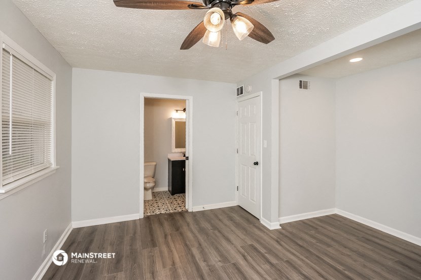 a living room with a ceiling fan and a door to a bathroom