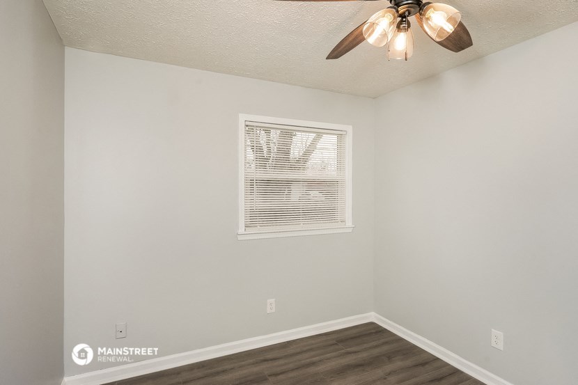 an empty bedroom with a ceiling fan and a window
