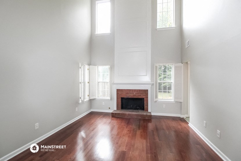 an empty living room with a fireplace and wooden floors