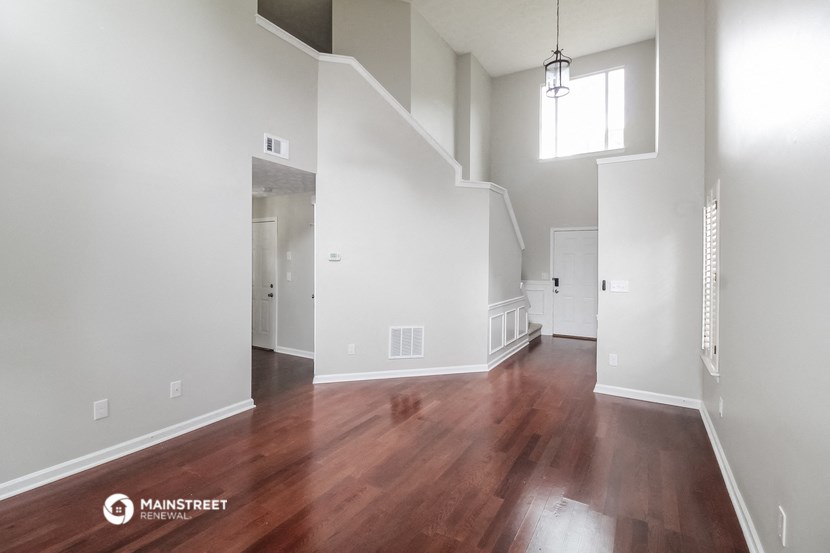 an empty living room with wood flooring and white walls