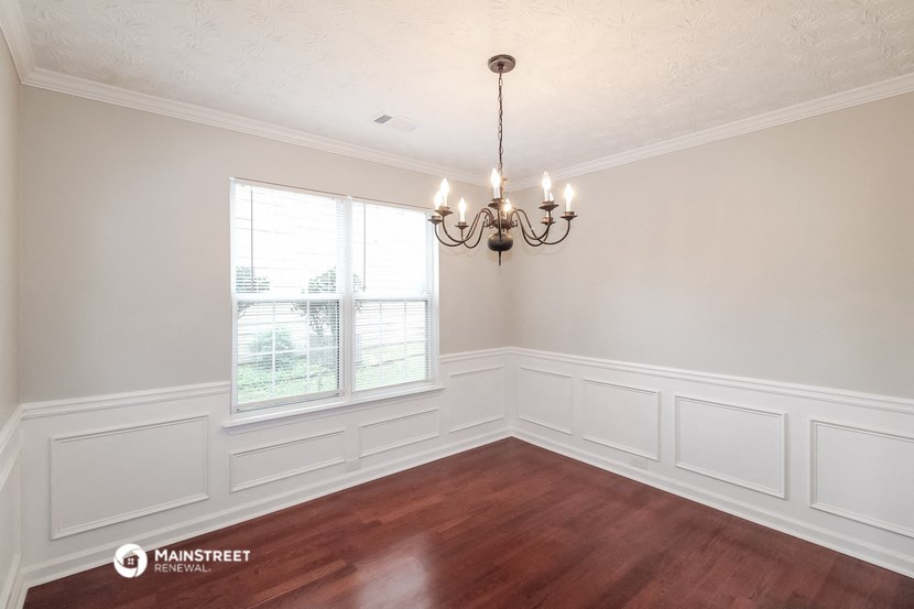 the dining room of a house with white walls and a chandelier