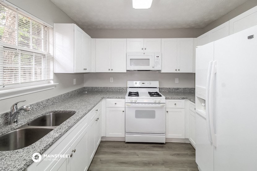 a white kitchen with granite counter tops and white appliances