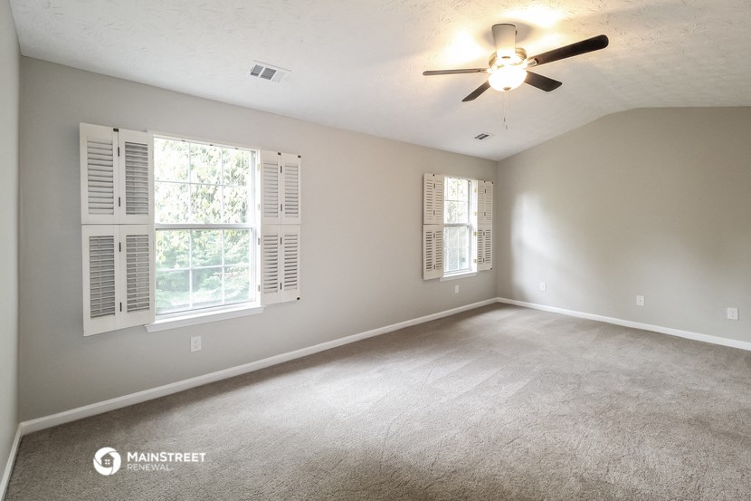 an empty living room with a ceiling fan and window