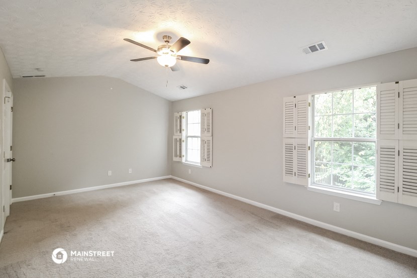 an empty living room with a ceiling fan and window
