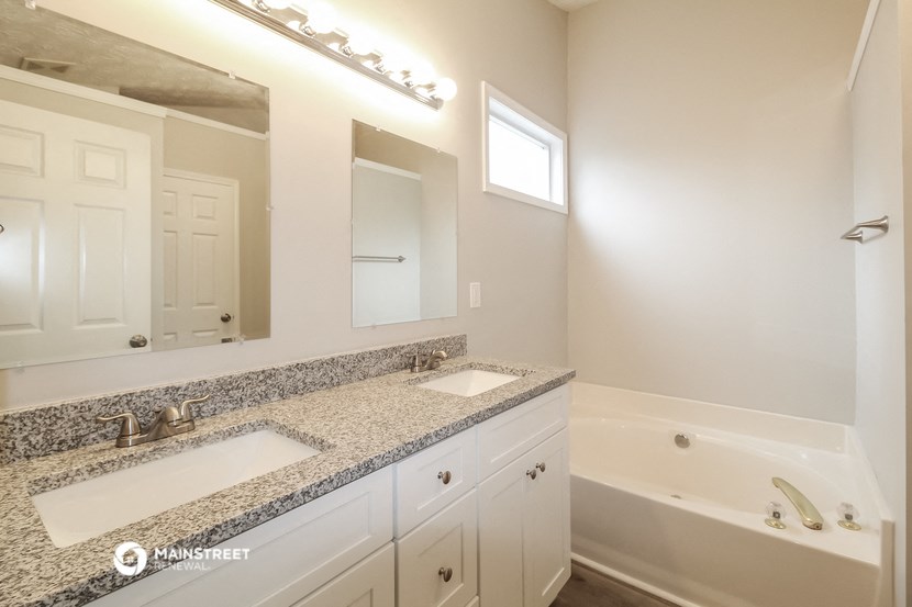 a bathroom with two sinks and a tub and a mirror