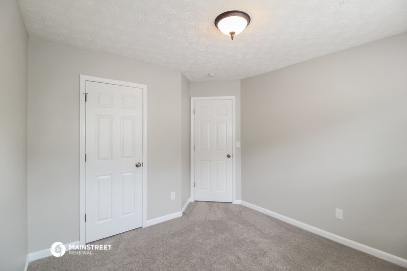 a bedroom with two doors and a carpeted floor