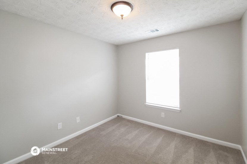 the upstairs bedroom with carpet and a window