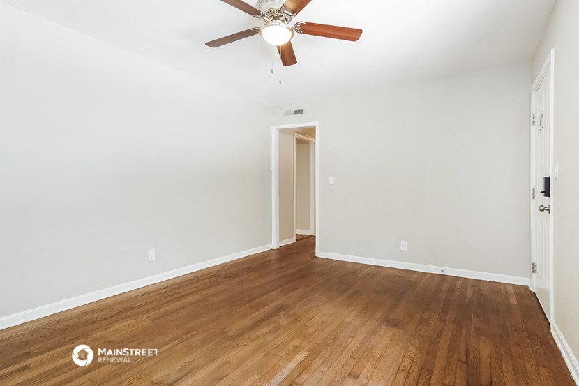 a living room with white walls and wooden floors and a ceiling fan