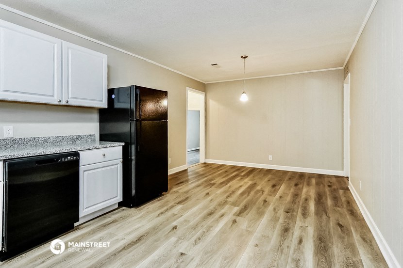 the kitchen and living room of an apartment with wood flooring and black appliances